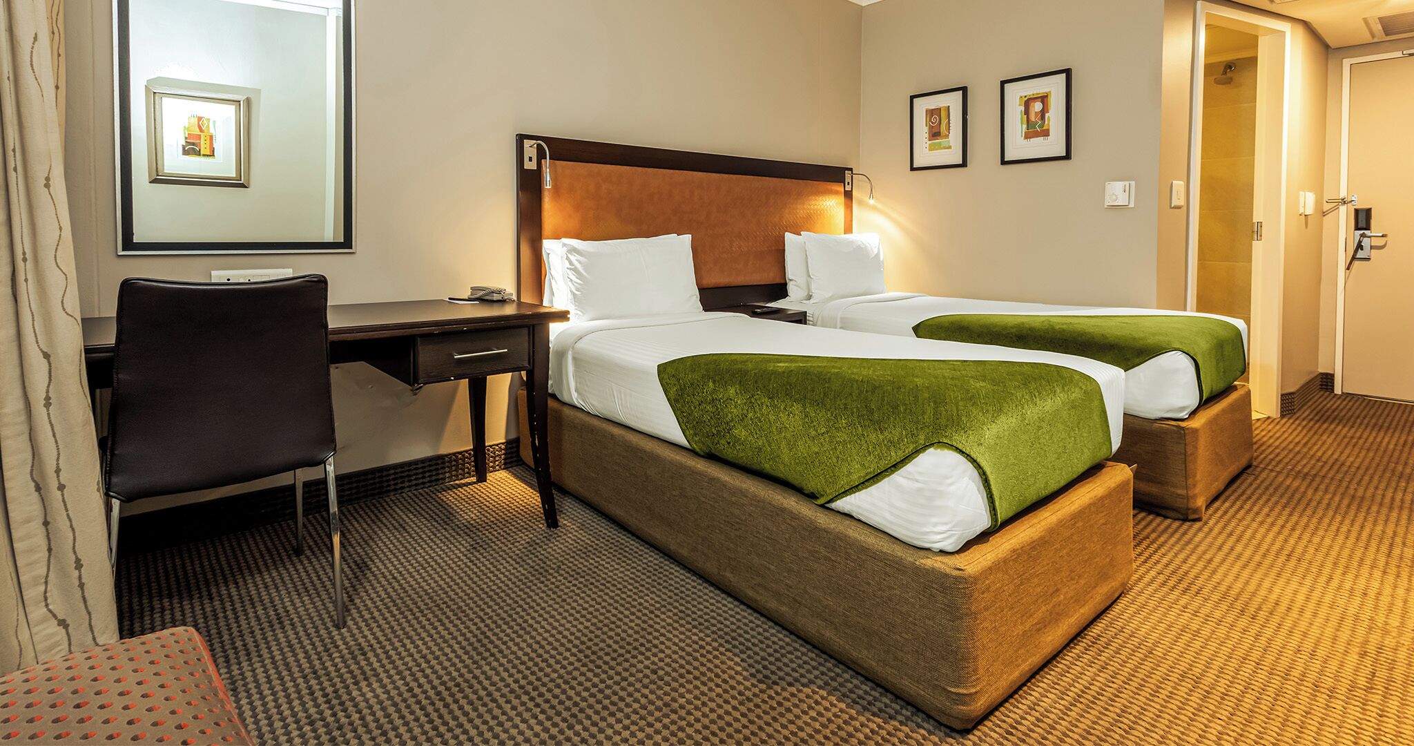 A hotel room with two beds, a desk, and a chair.