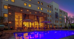 A hotel with a pool, outdoor seating, and a modern architectural design.