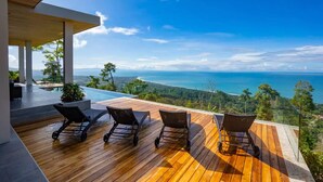 A wooden deck with outdoor seating and a view of the ocean.