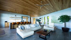 A modern living room with a sectional sofa, a coffee table, and a dining area with a large window.
