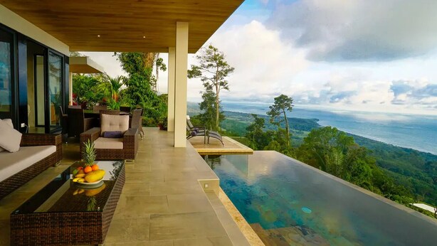 A modern outdoor lounge area with a pool overlooking a scenic landscape.
