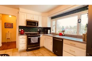 Enjoy cooking in this well-equipped kitchen with a large window offering a view of the outdoors, a microwave, and a sink.