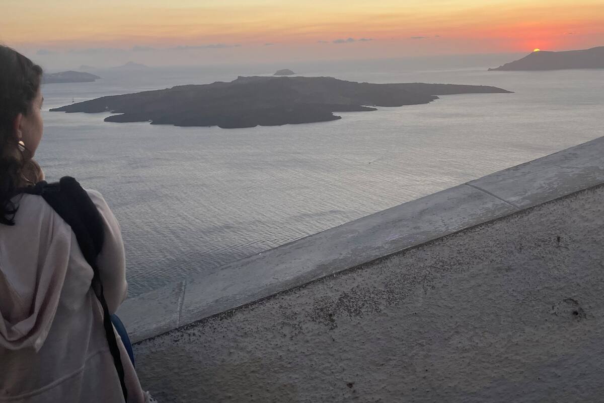 A person overlooking a coastal landscape with a sunset.