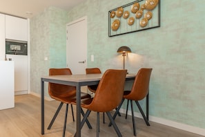 Uma sala de jantar com uma mesa e cadeiras, um abajur e uma parede decorada com pratos.