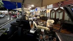 An outdoor restaurant with tables and chairs, a counter, and a sign for Cantinho da Serra.