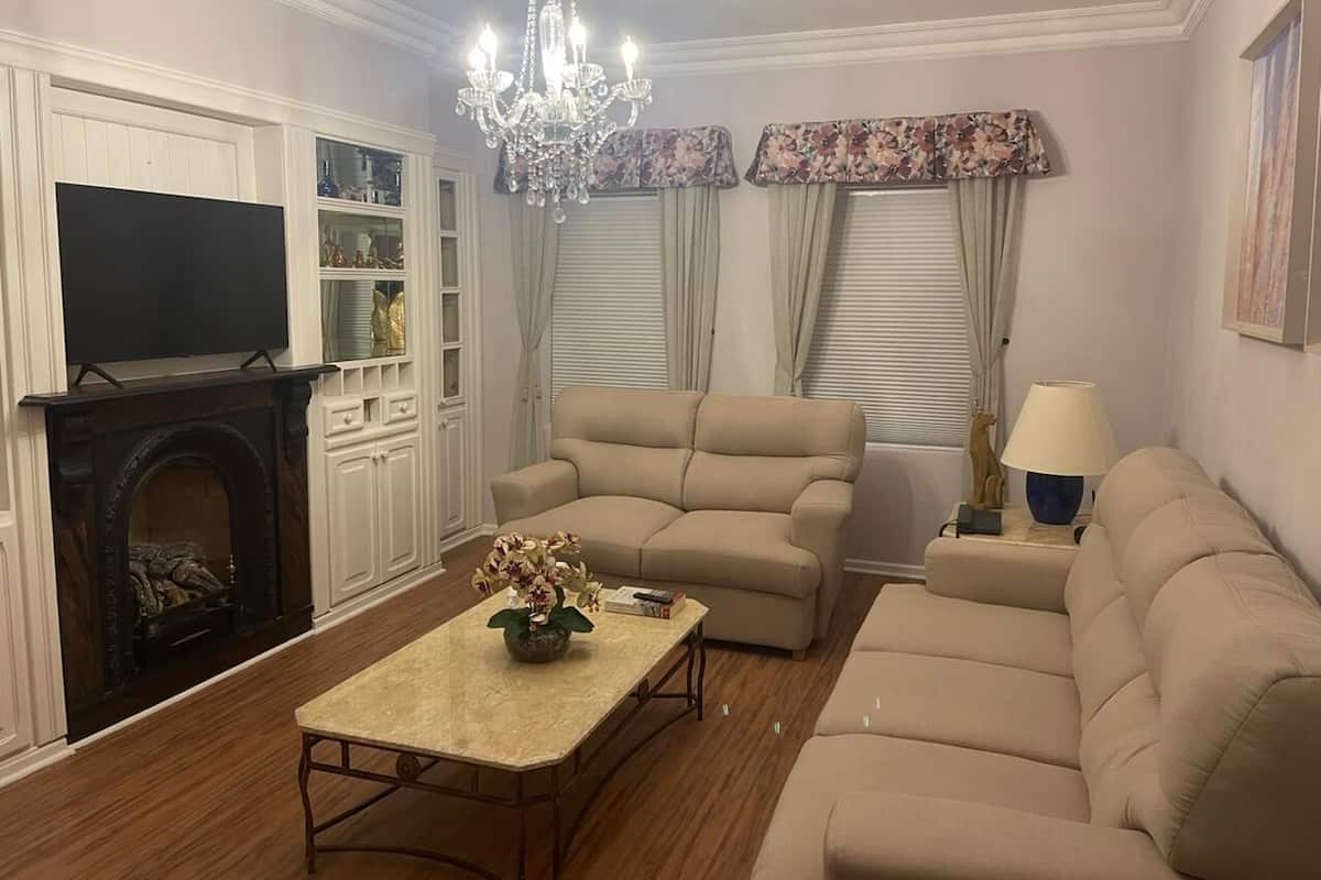 A living room with a fireplace, a beige sofa, a coffee table, and a chandelier.