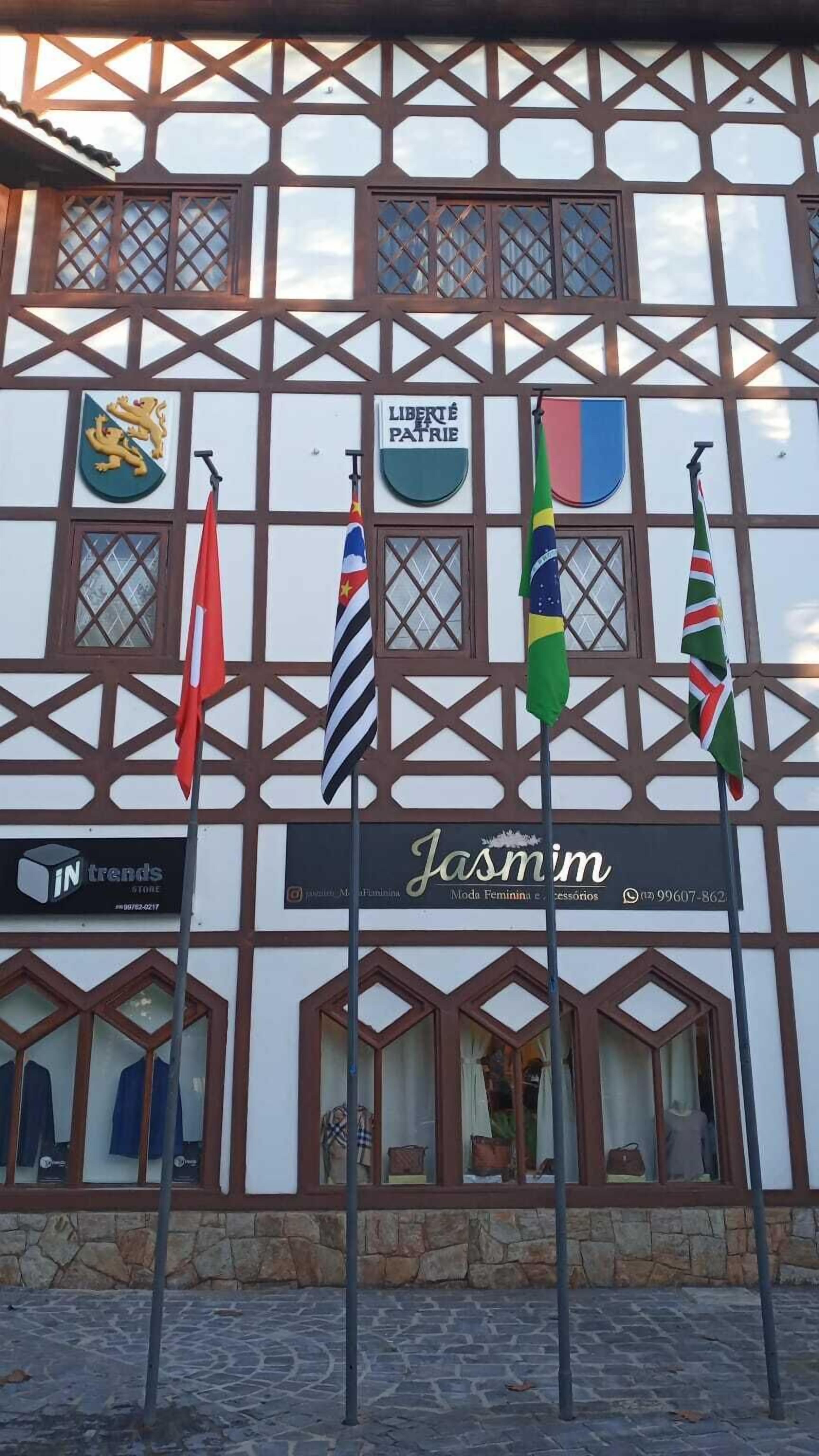 A building with multiple flags, including a sign that reads "LIBERTÉ PATRIE" and a storefront named "Jasmine".