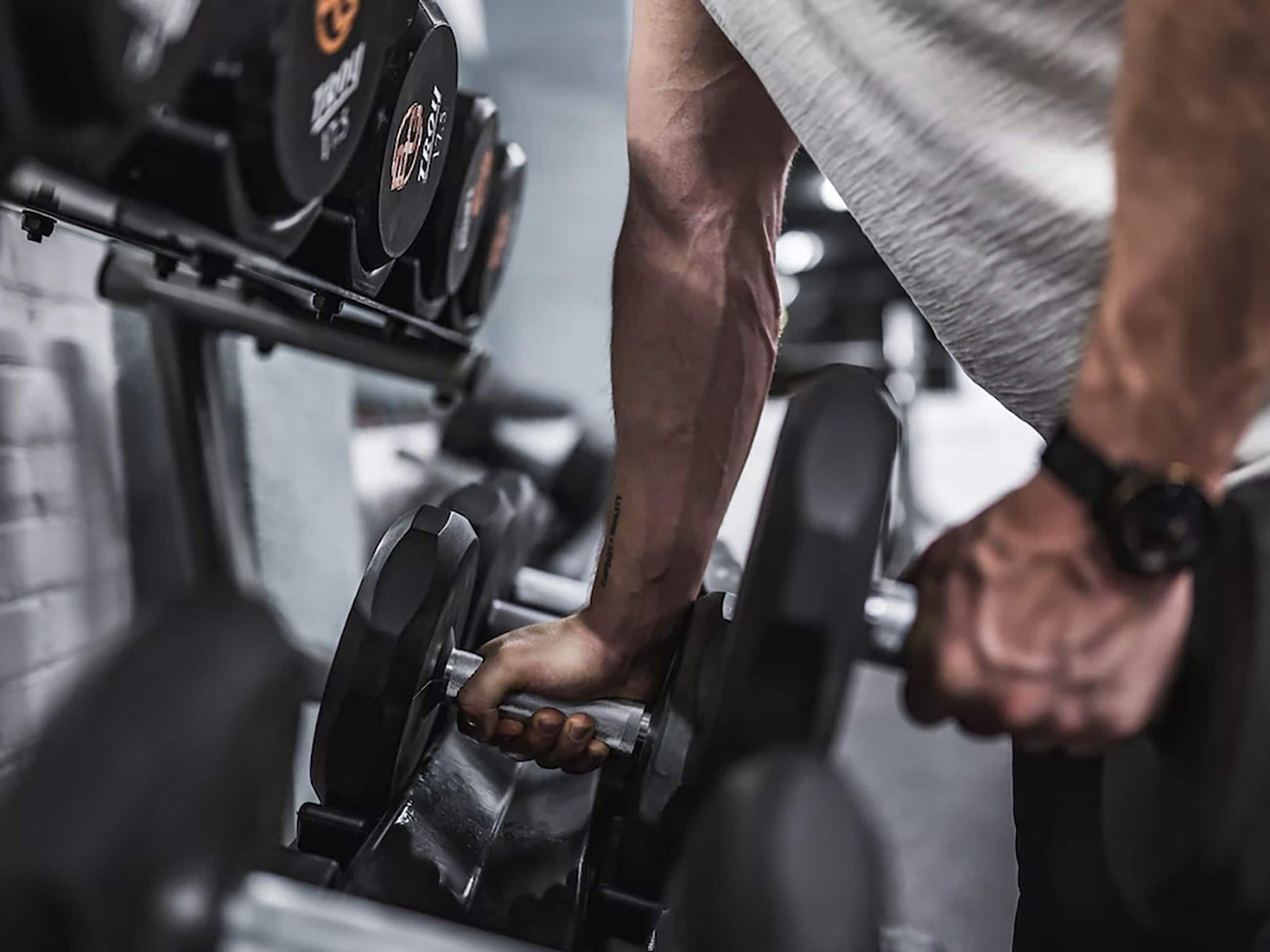 Primer plano de una persona levantando pesas en un gimnasio.