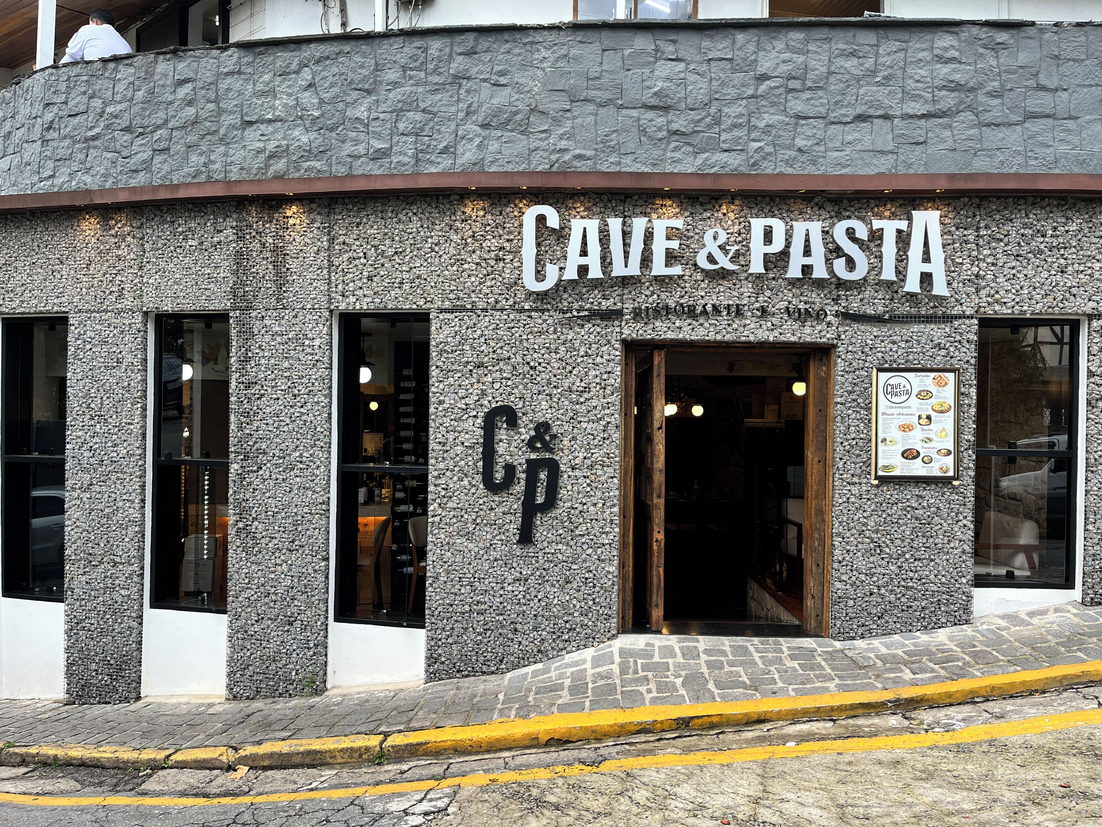 A building facade with a sign reading "CAVE & PASTA" and a menu board on the right.