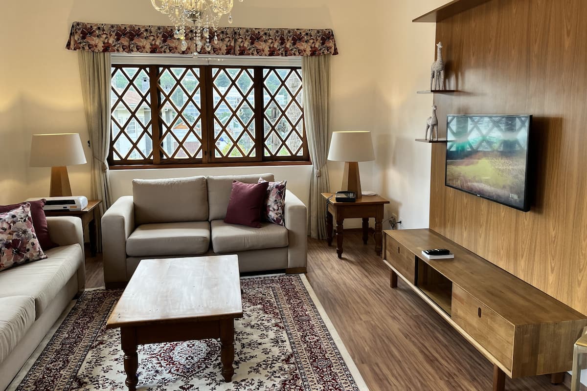 A living room with a sofa, two lamps, a coffee table, a TV, and a patterned rug.