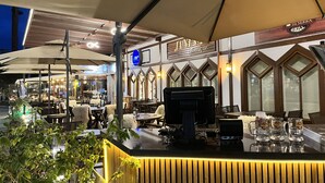 An outdoor restaurant with a bar area, tables, and umbrellas.