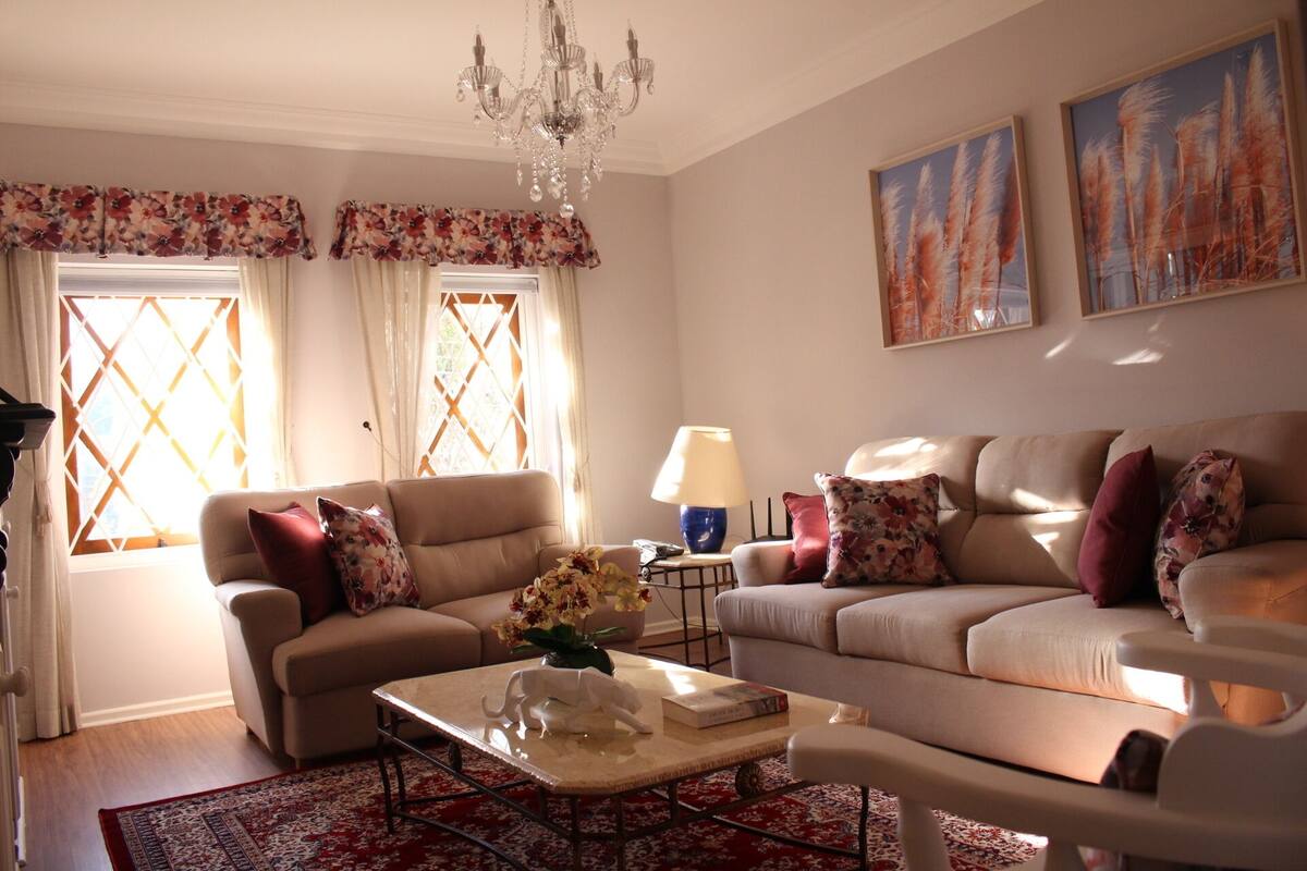 A living room with two sofas, a coffee table, a chandelier, and artwork on the walls.