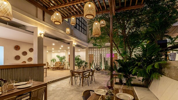 An indoor dining area with wooden tables, wicker chairs, and hanging wicker lamps. - Soy Local Santa Marta  (Santa Marta)