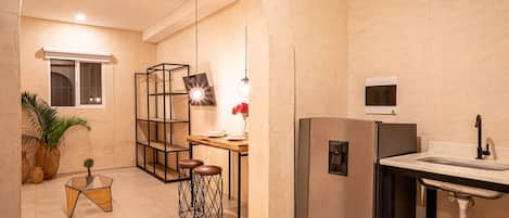 A modern kitchen with a built-in refrigerator, a sink, and a dining area with stools.
