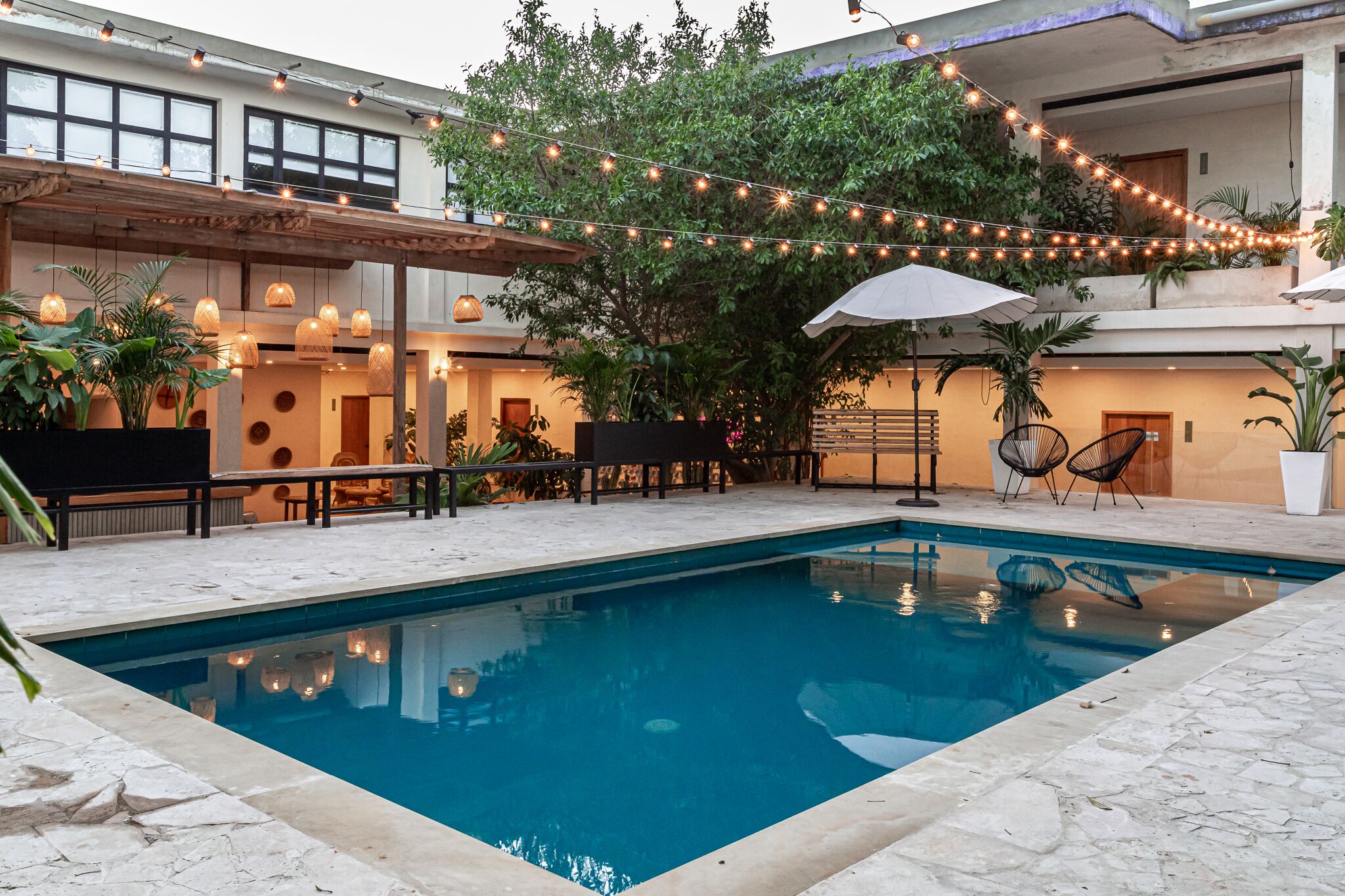 A pool area with a clear blue pool, surrounded by stone tiles, and furnished with outdoor seating.