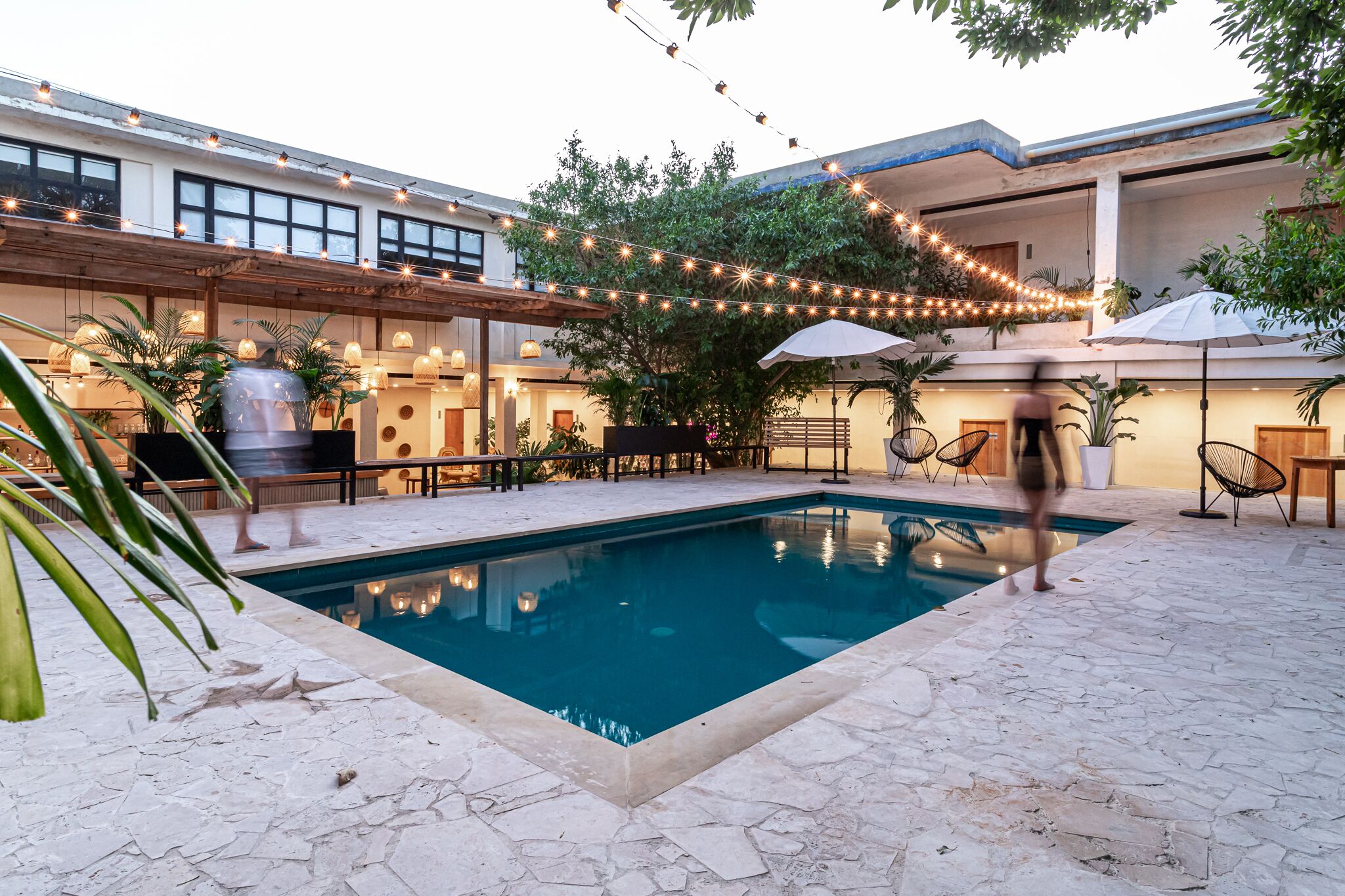 A pool area with string lights, umbrellas, and outdoor seating.