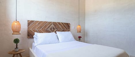 Ein Schlafzimmer mit einem Bett, zwei Hängelampen, einem kleinen Tisch mit einer Pflanze und einer Wand-Klimaanlage.
