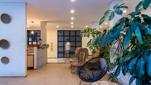 A modern interior with wicker furniture, a large potted plant, and a kitchen area. - Soy Local Santa Marta  (Santa Marta)