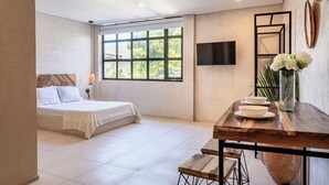 A modern bedroom with a bed, a wooden table with bowls, a vase of flowers, and a TV on the wall. - Soy Local Santa Marta  (Santa Marta)