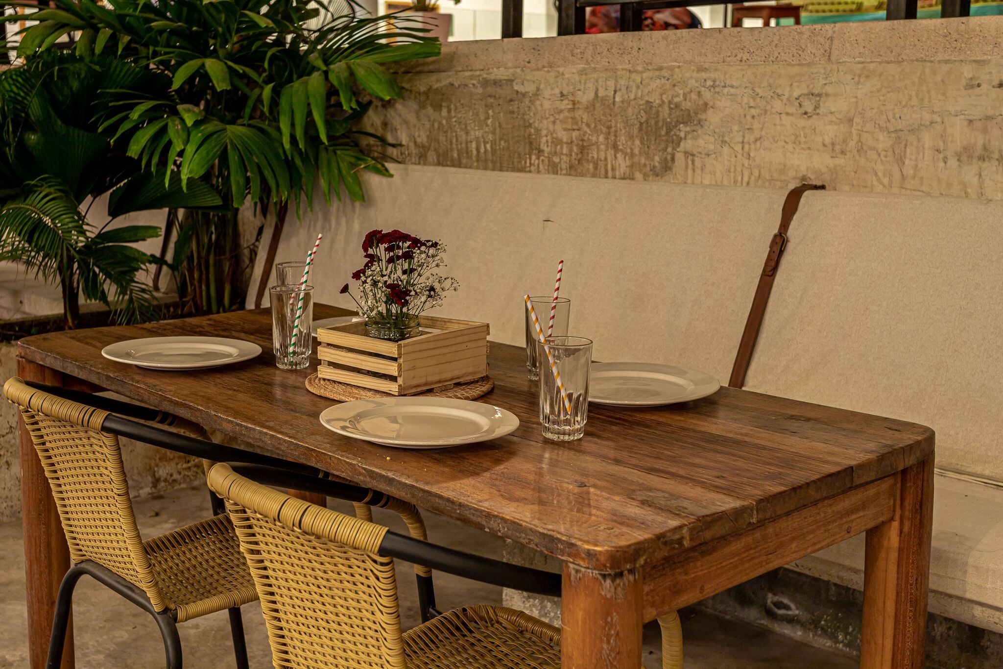 Una mesa de comedor de madera dispuesta con platos, vasos y un centro de mesa floral.