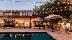 An outdoor pool area with string lights, benches, and umbrellas. - Soy Local Santa Marta  (Santa Marta)