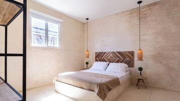 Un dormitorio con cama, ventana, repisa montada en la pared y lámpara colgante.