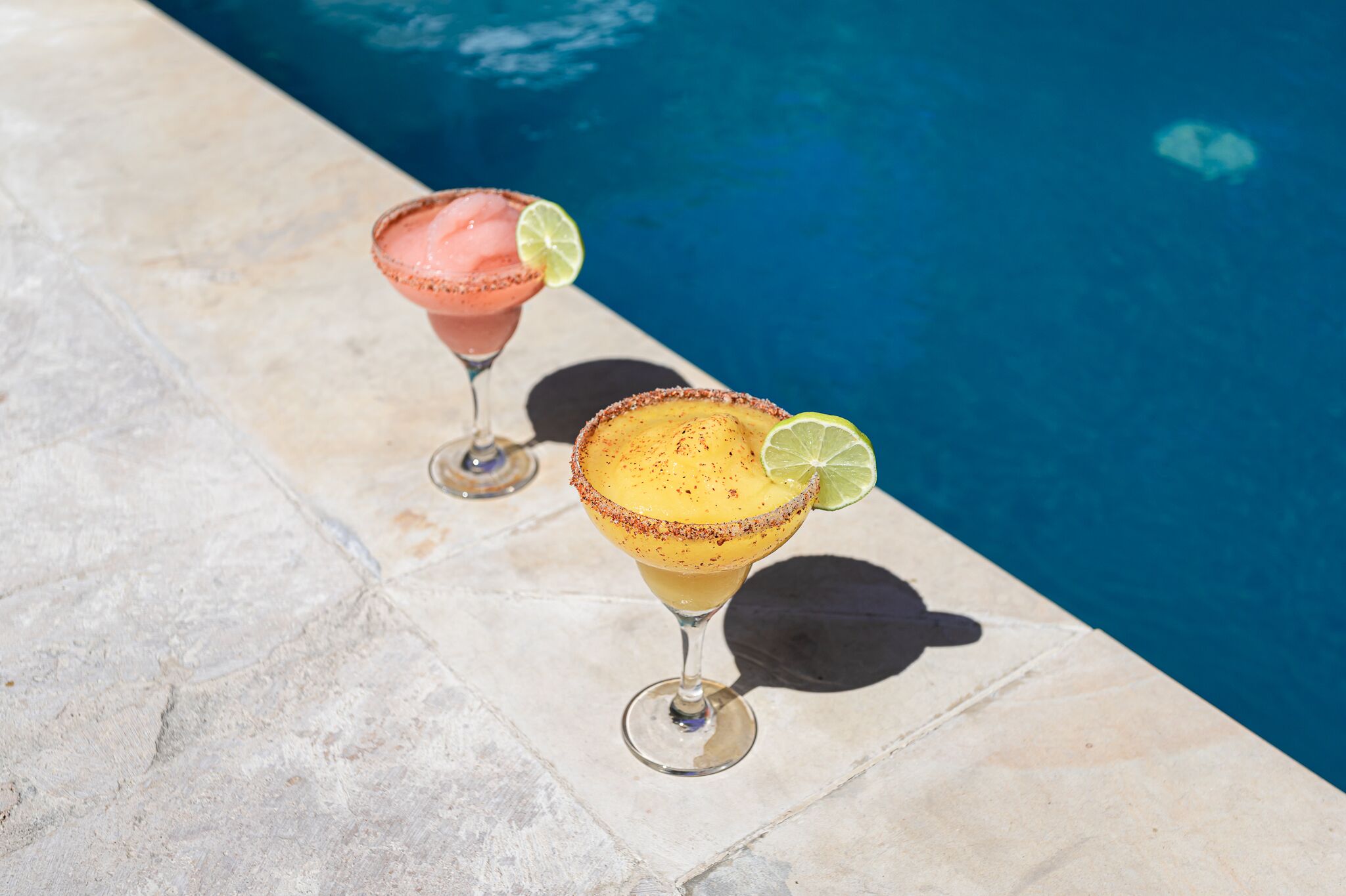 Deux margaritas sur une table au bord de la piscine, avec la piscine en arrière-plan.