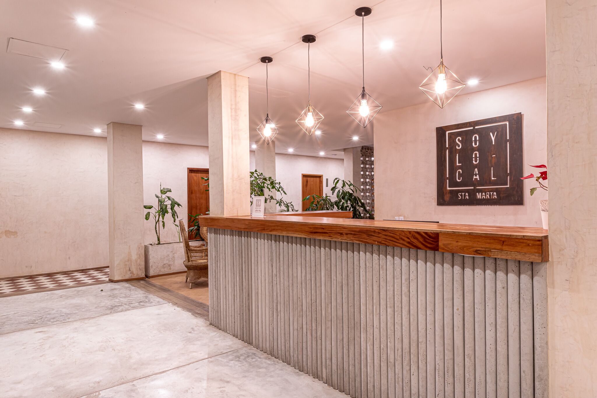 A reception area with a wooden counter, hanging pendant lights, and a wall-mounted sign.