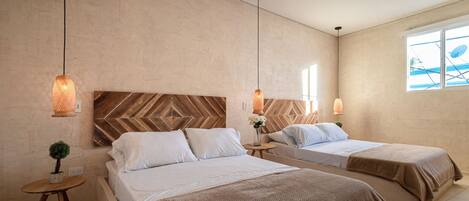 A hotel room with two beds, a large window, and a herringbone-patterned headboard.