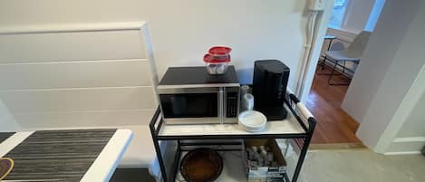 A kitchenette with a microwave, coffee maker, and a box of breakfast blend coffee.
