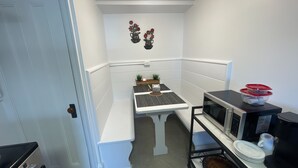 A compact kitchen with white cabinetry, a microwave, a coffee maker, and a small table with a tray. - Studio-like Comfort in Wolfville’s Beating Heart (Wolfville)