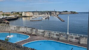 Un port de plaisance avec des bateaux, une piscine et, en arrière-plan, un bâtiment historique.
