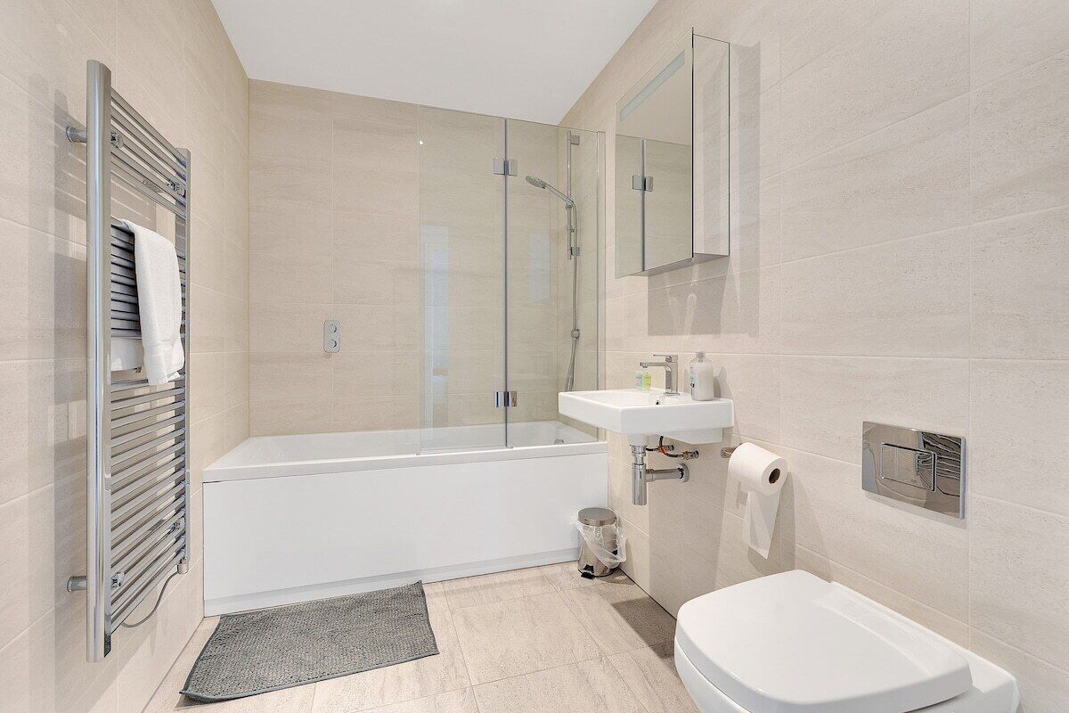 Une salle de bain moderne avec une douche à parois de verre, une baignoire blanche, un lavabo avec un miroir au-dessus et des toilettes.
