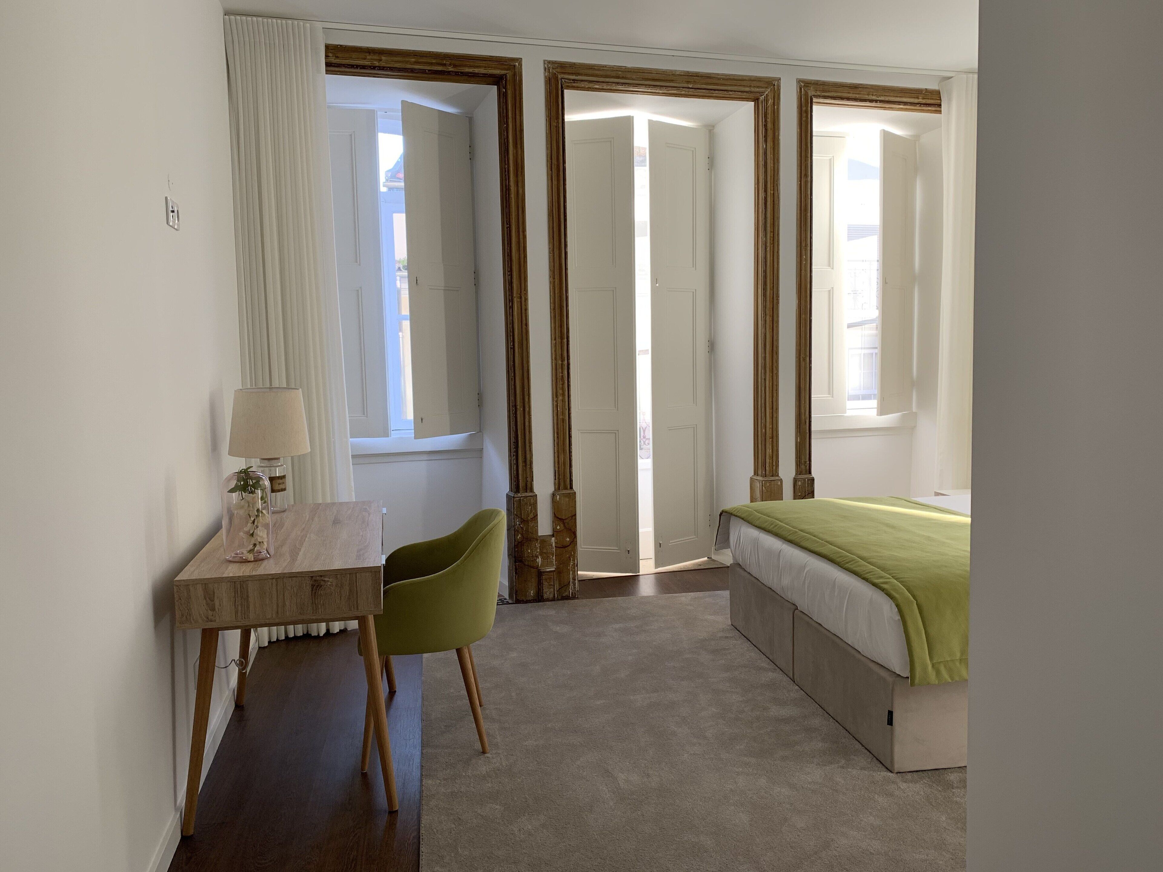 A bedroom with a bed, a desk, a chair, and a window.