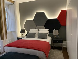A modern bedroom with a large bed, two bedside tables, and a geometric wall design. - Pharmacia Guest House (Coimbra)