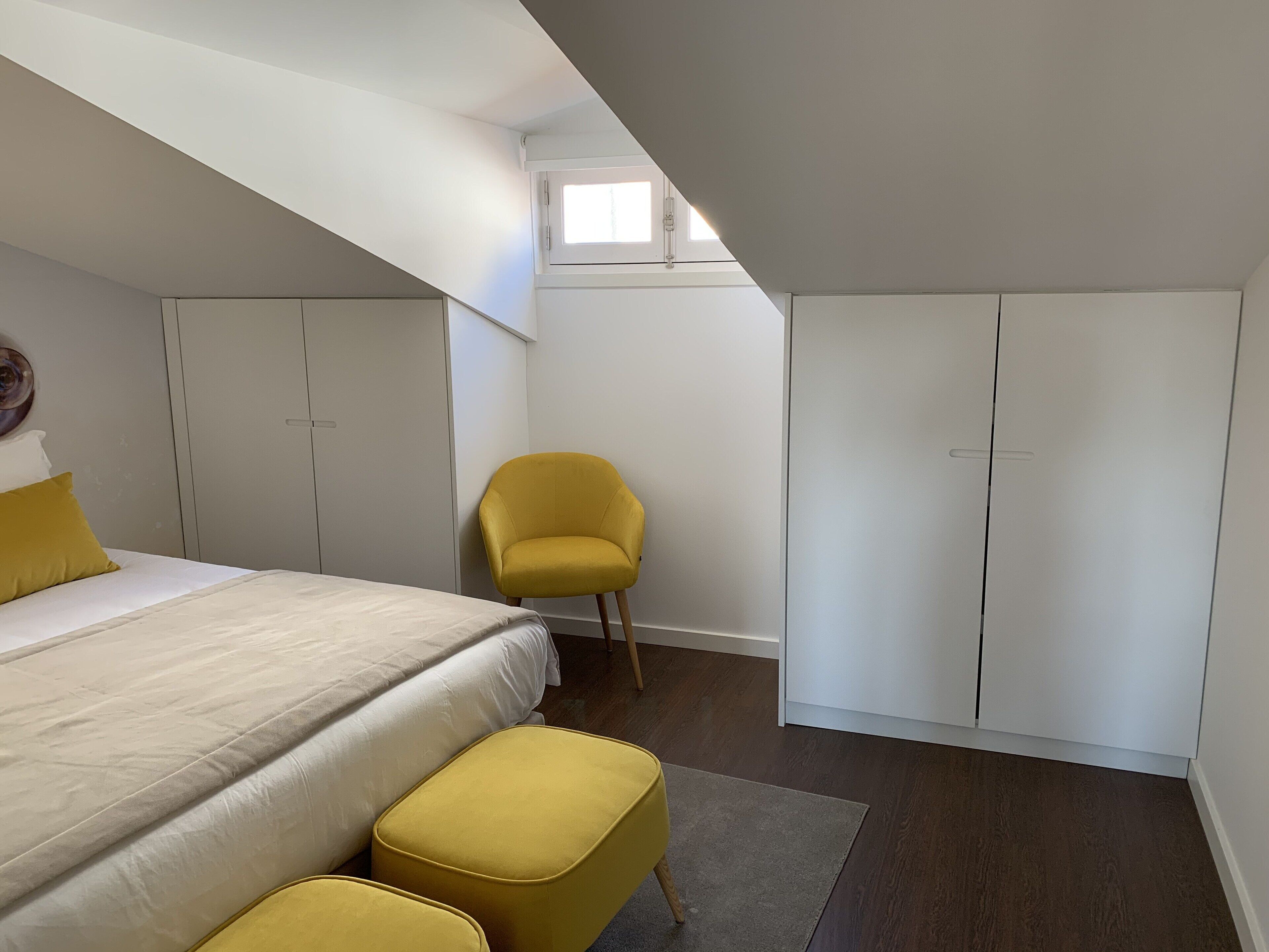 A bedroom with a bed, a yellow chair, and wardrobes.