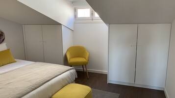A bedroom with a bed, a yellow chair, and wardrobes.