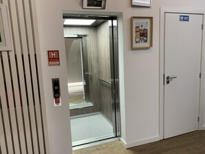 An elevator with a mirrored wall, a fire safety sign, and a door with a "WC" sign. - Pharmacia Guest House (Coimbra)