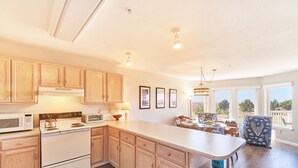 A spacious kitchen with wooden cabinets, a central island, and a dining area with a view. - Amazing Ocean Views, Pets Ok, Walk To Town and Beach (Breeze) (Long Beach)