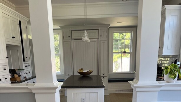 Une cuisine spacieuse avec des meubles blancs, un îlot central et un plancher en bois.