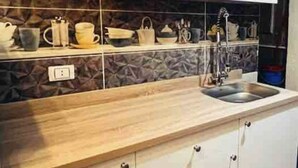Une cuisine moderne avec un dosseret en pierre, des armoires en bois et un évier en acier inoxydable.
