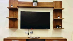 Un meuble de rangement en bois pour appareils multimédias, doté d’un téléviseur à écran plat, d’étagères intégrées et d’une table basse.