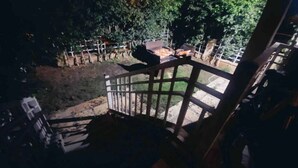 Un escalier menant à un balcon d’où l’on peut admirer un jardin et un espace repas.