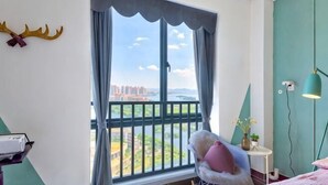 A room with a large window, a chair, a lamp, and a wall-mounted decoration. - Huayuan Homestay (Huangshang Scenic Area South Gate) (Huangshan City)