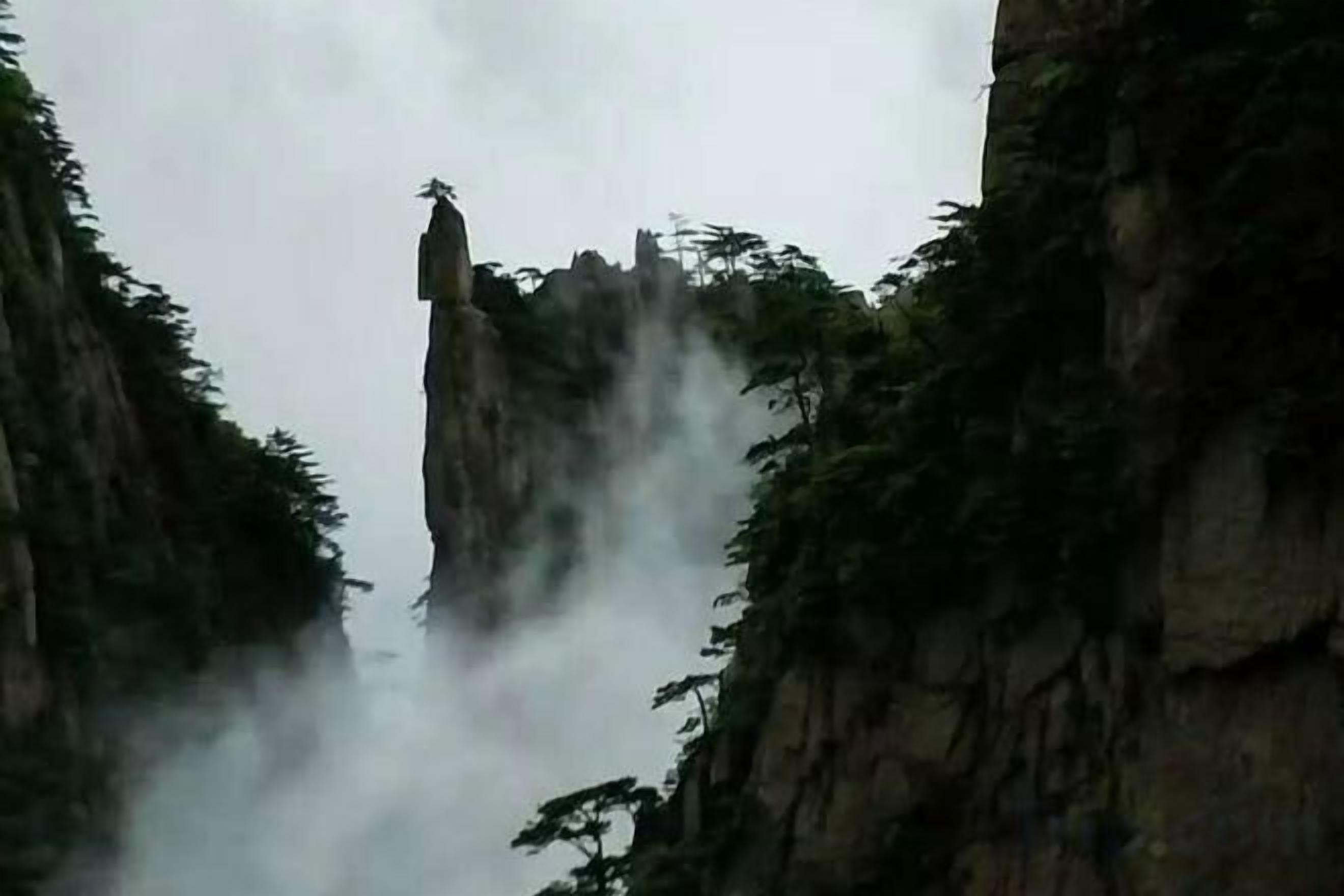 Un paisaje montañoso con una formación rocosa destacada y vegetación densa.