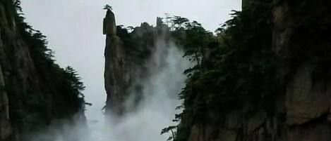 Un paisaje montañoso con una formación rocosa destacada y vegetación densa.