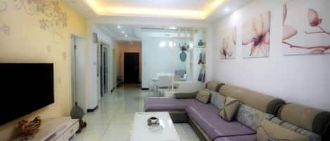 A modern living room with a sofa, a coffee table, a TV, and decorative wall art.