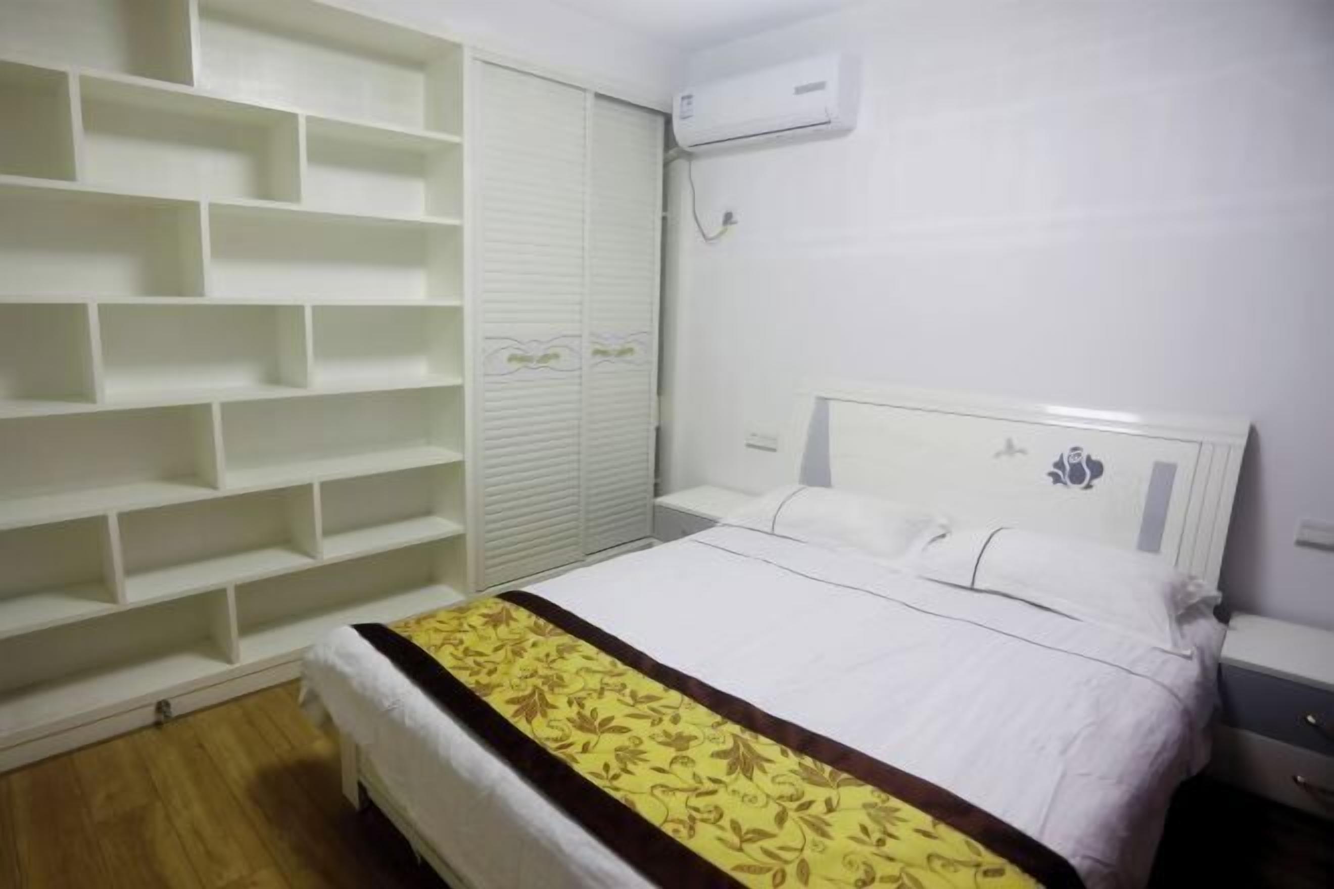 A bedroom with a bed, a wardrobe, and a bedside table.
