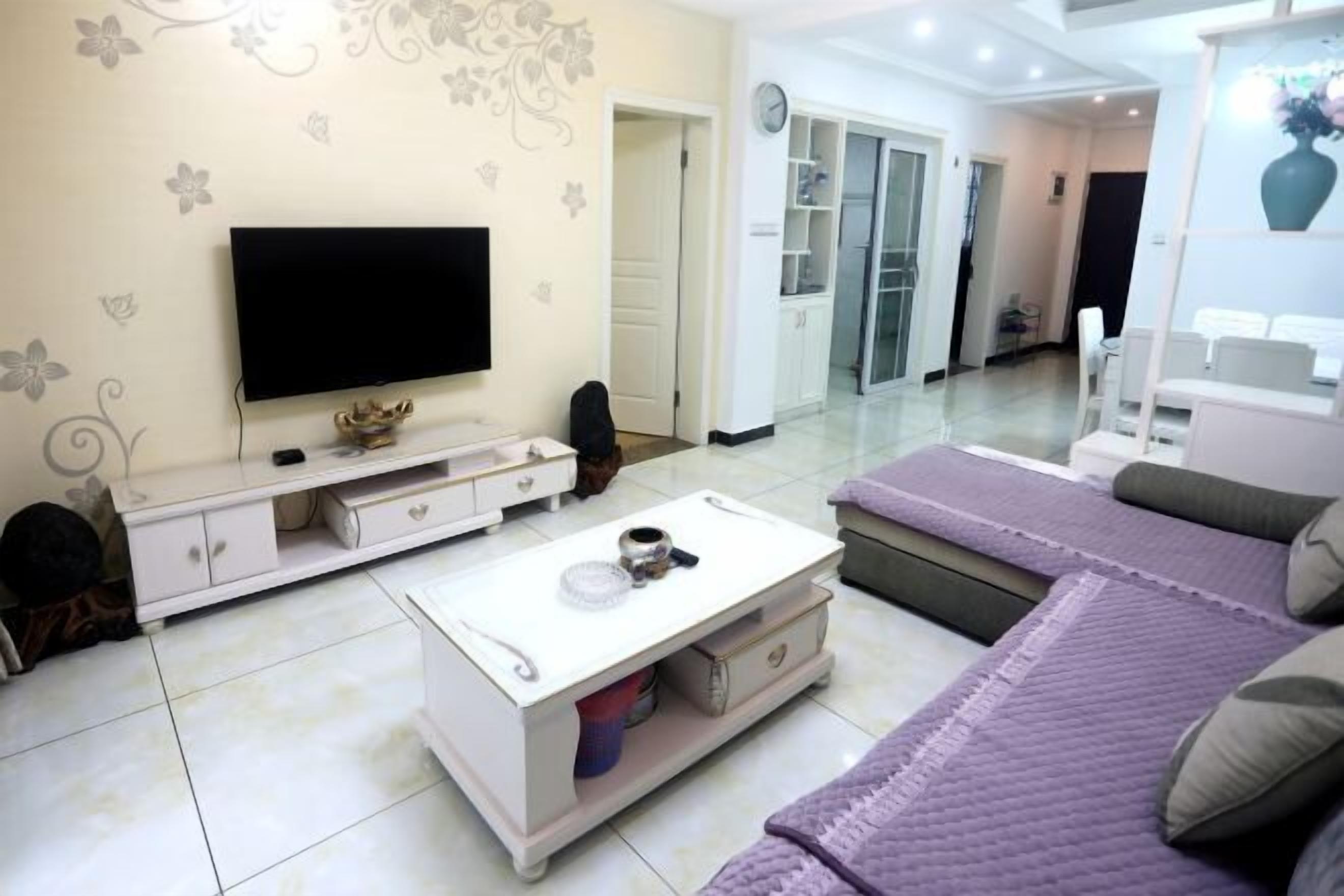 Una sala de estar con televisor, sofá, mesa de centro y un comedor con sillas.