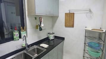 A kitchen with a double sink, a stove, and a metal rack with containers.